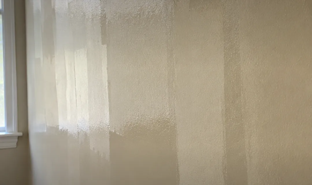 Parede pintada com faixas e marcas de emenda aparecendo com a luz da janela